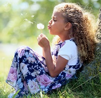 Girl blowing a dandelion